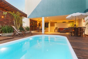 A swimming pool with wooden deck, lounge chairs, and a table with chairs. - Valencia Hotel Natal (Natal)