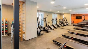 Een sportschool met hometrainers, loopbanden en een klimmuur.