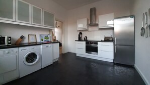 A modern kitchen with a washing machine, oven, and stainless steel refrigerator. - Ferienwohnung Stricker Bad Sachsa (Bad Sachsa)