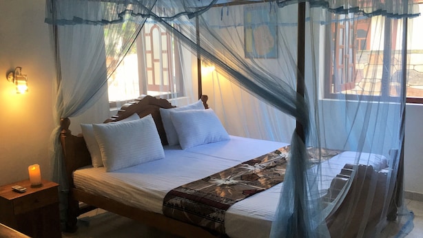 Een bed met hemel, witte kussens en een bedovertrek met dessin.