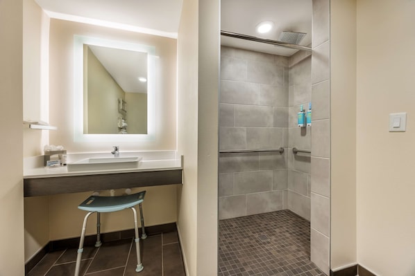 Une salle de bain avec un lavabo, un miroir et un espace douche.