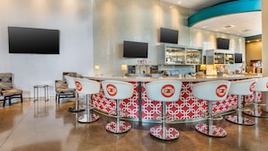 A bar area with a curved counter, multiple bar stools, and a seating area with chairs.