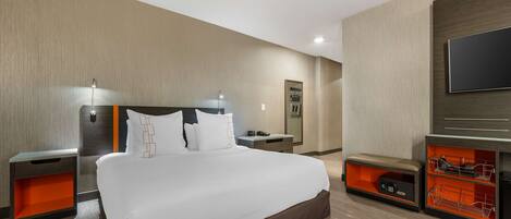 Une chambre d’hôtel moderne dotée d’un grand lit, de tables de chevet, d’un téléviseur et de rangements intégrés.