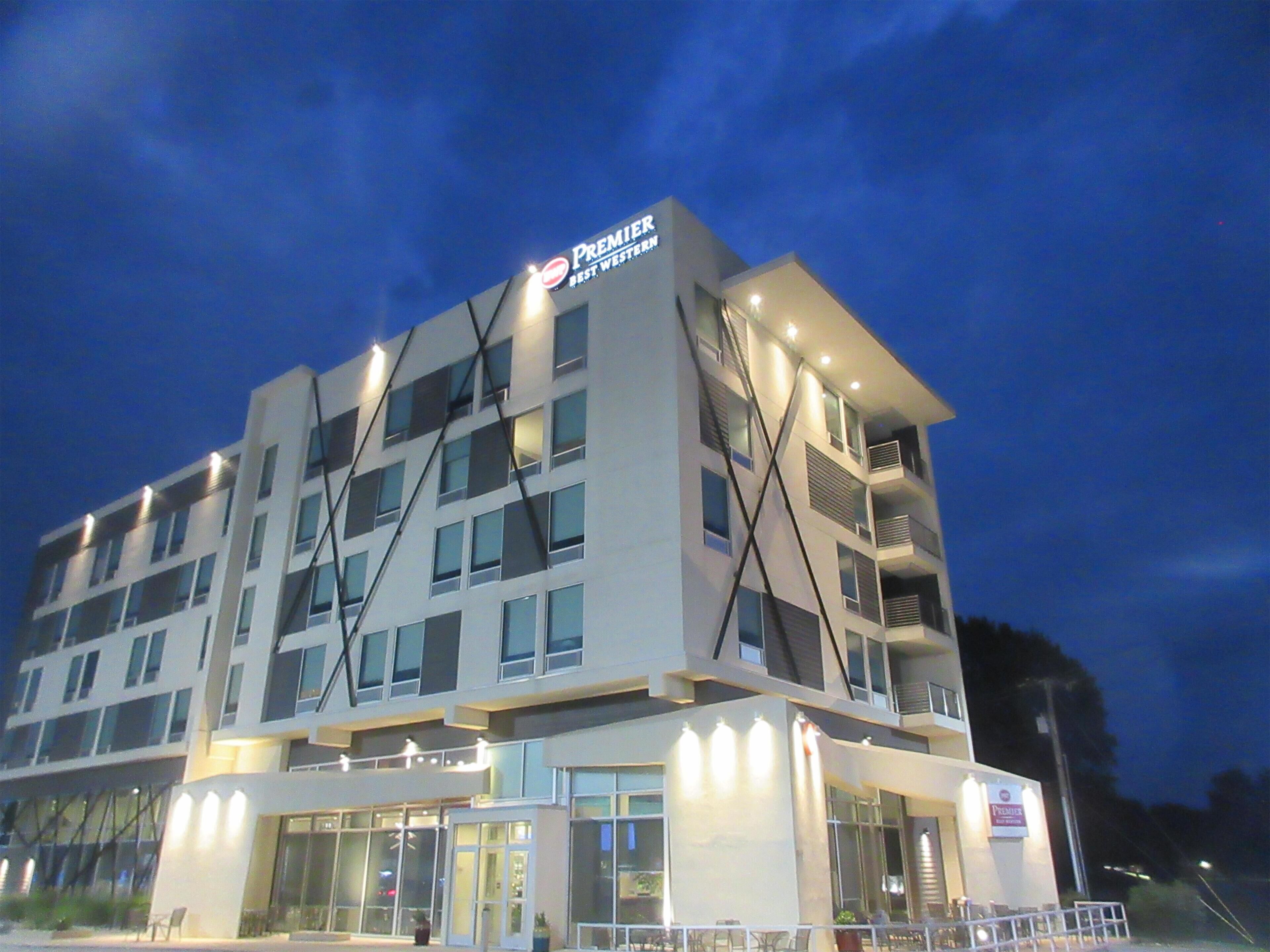 A multi-story hotel with a prominent 'Premier' sign, large windows, and a flat roof design.