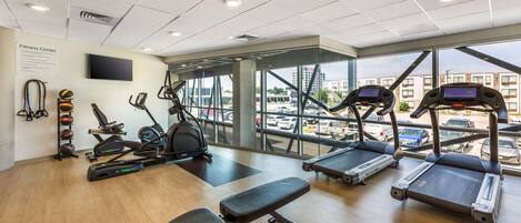A fitness center with treadmills, elliptical machines, and a bench.
