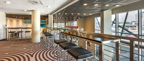 A modern bar area with high stools and a patterned carpet.