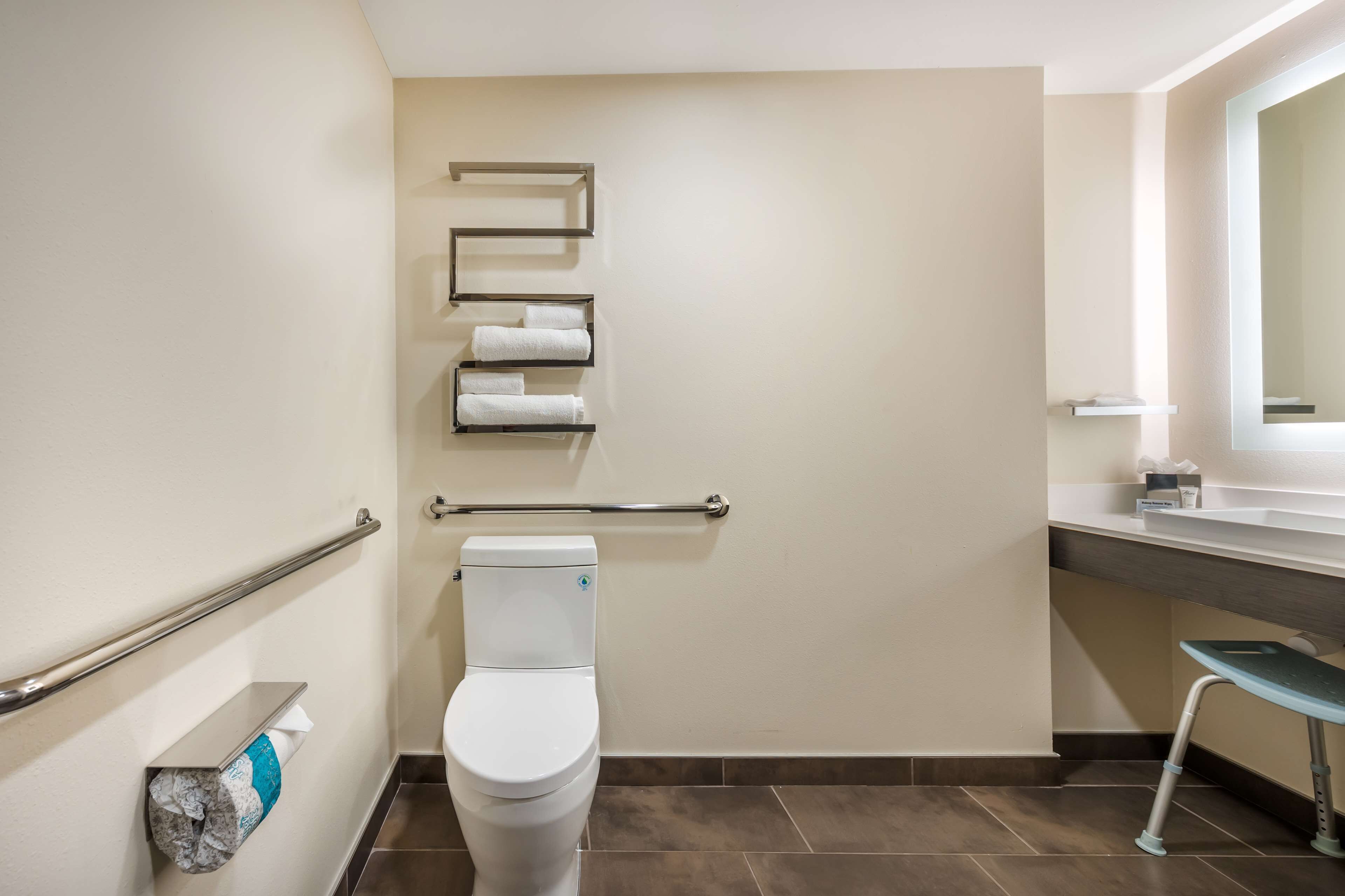Een badkamer met toilet, handgreep, handdoekhouder en wastafel.
