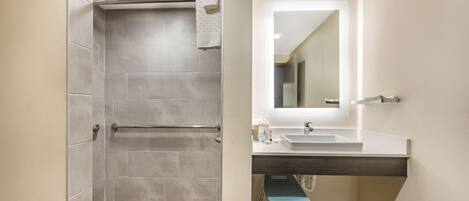 A modern bathroom with a shower, a sink, and a mirror.