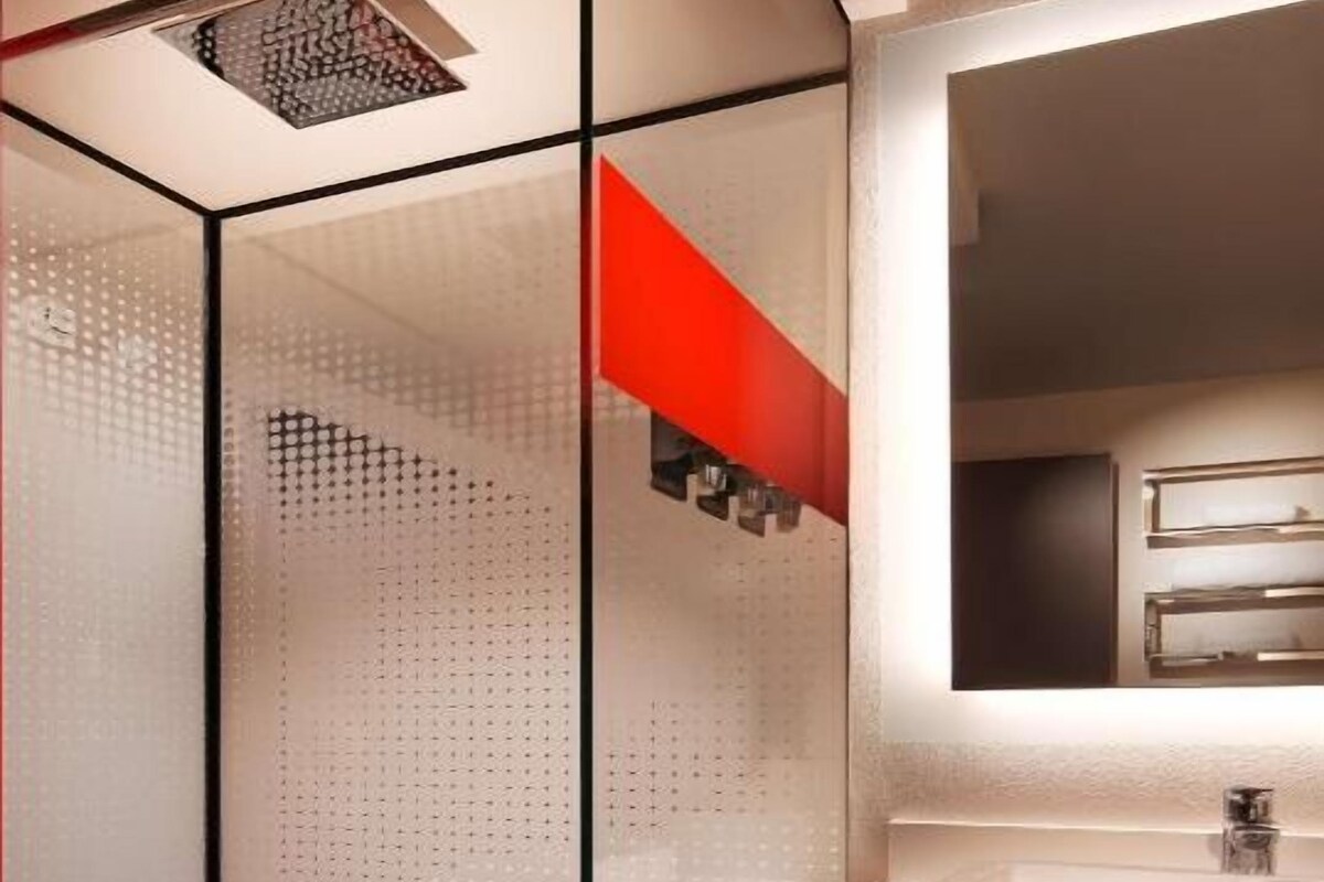 Une salle de bain moderne avec une douche à l’italienne en verre, un lavabo blanc et un meuble-lavabo foncé.