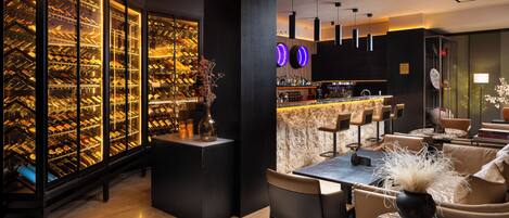 A modern bar area with a wine cellar, bar stools, and a seating area with a table and chairs.