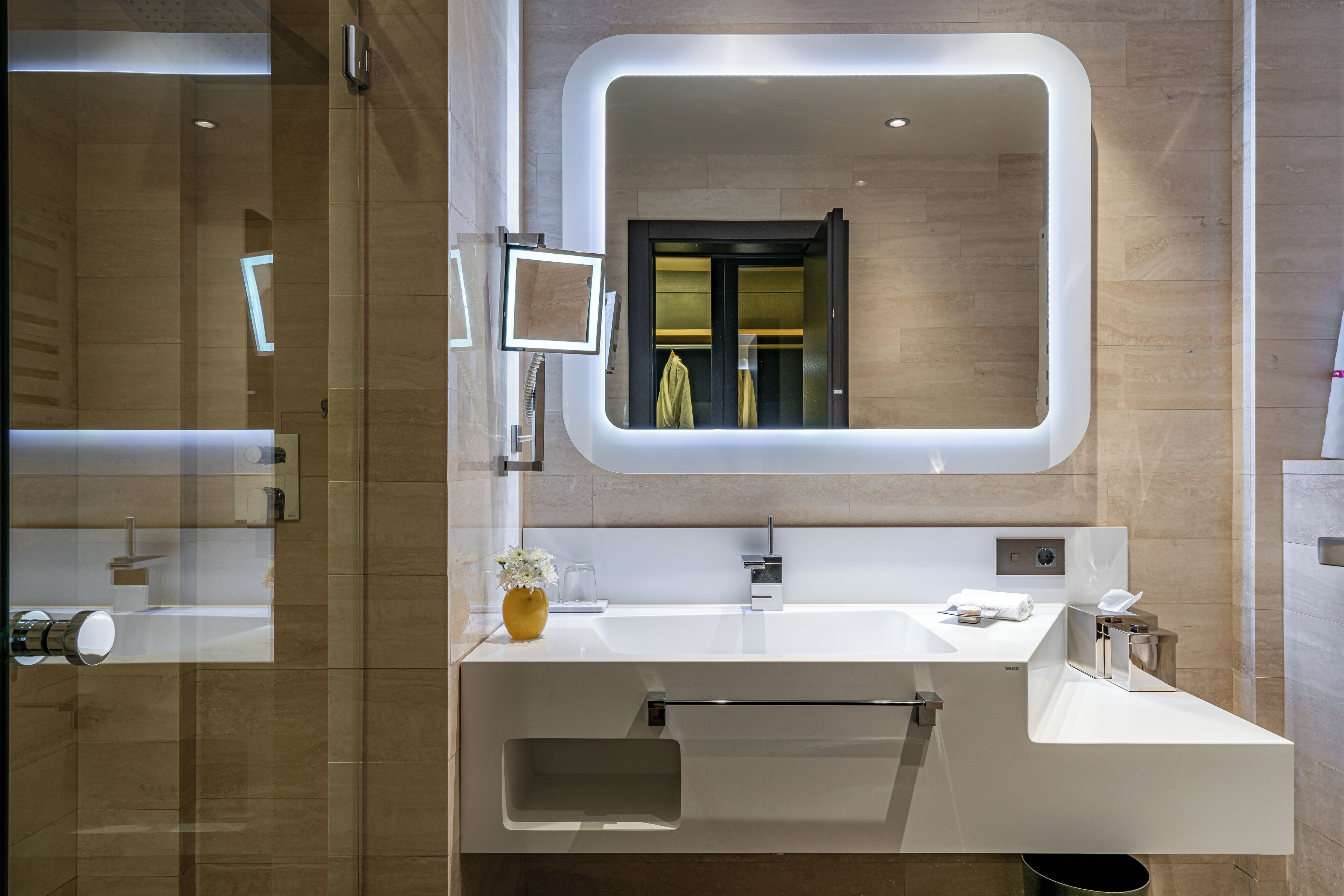 Un baño moderno con un espejo grande, un lavabo y un perchero para toallas.
