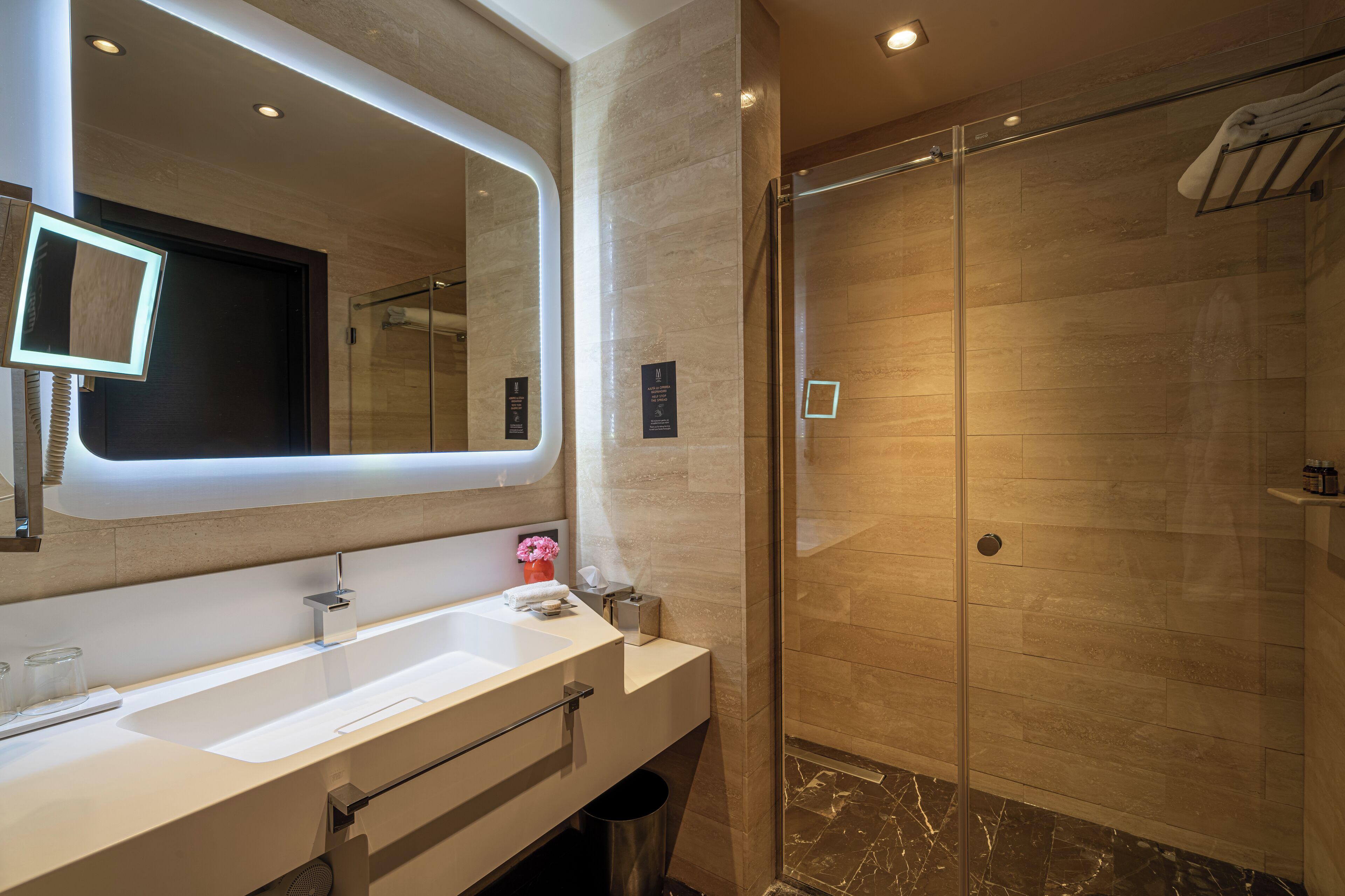 Une salle de bain moderne avec un grand miroir, un lavabo et une douche à parois de verre.
