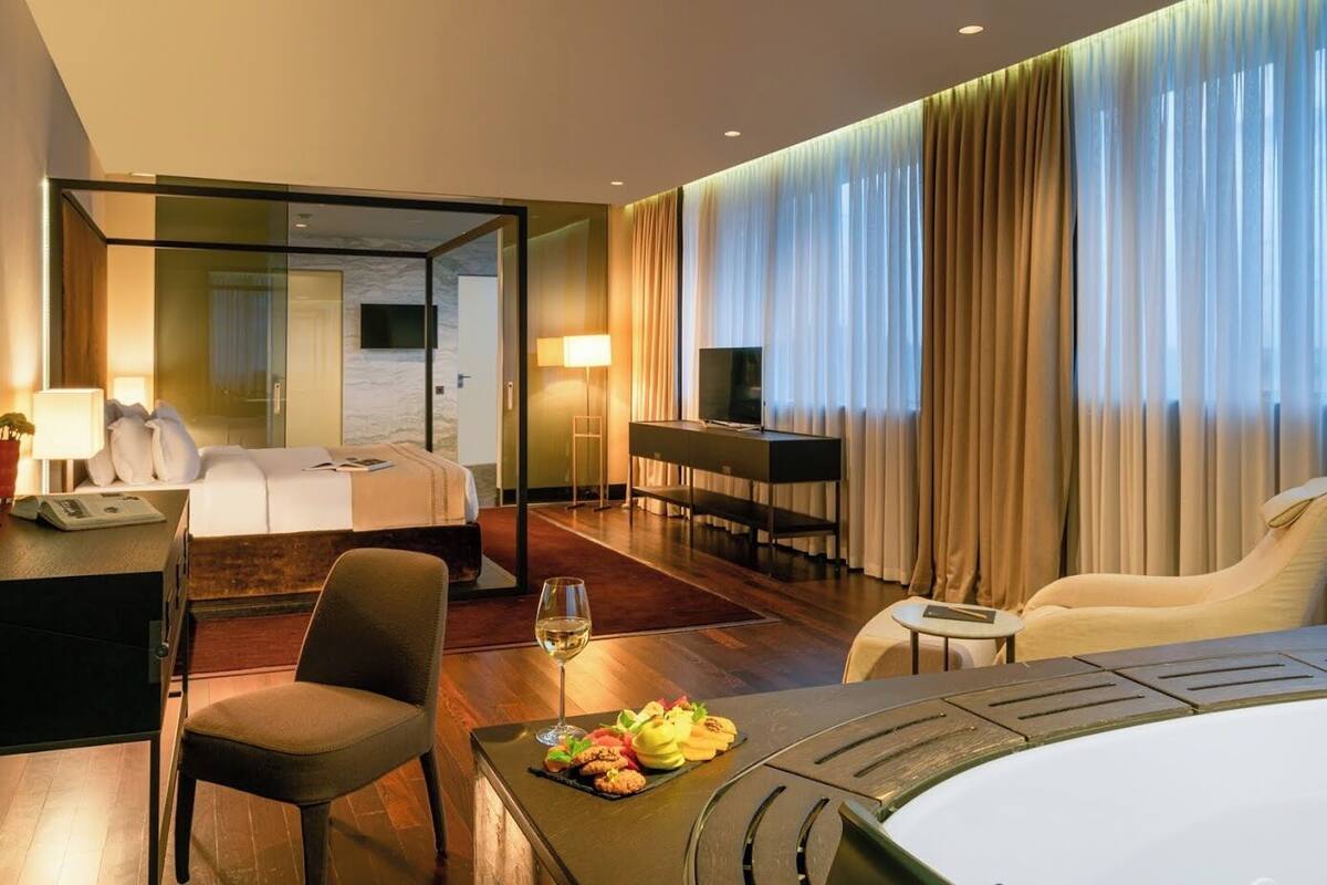 Una habitación de hotel con cama, escritorio, televisor, sofá y mesa de comedor con comida.