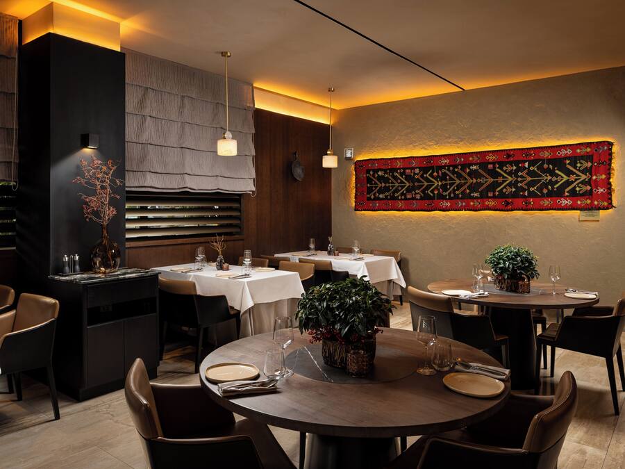 Un ristorante con tavoli rotondi, sedie e un pannello decorativo a parete.