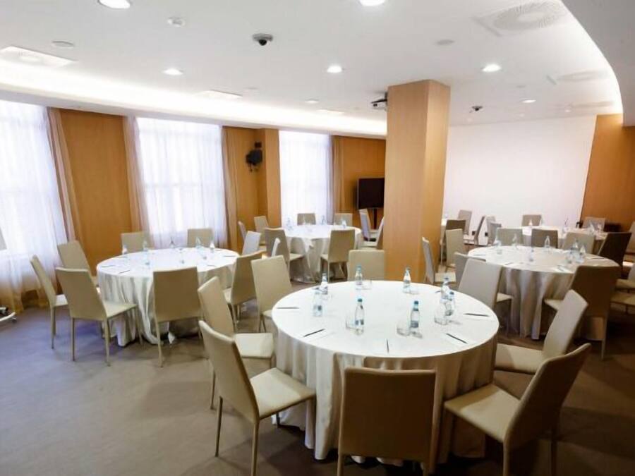 A conference room with multiple round tables, white chairs, and a whiteboard.