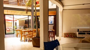 Amplio espacio interior con mesas y sillas de madera, una mesa de vidrio al frente y un árbol de Navidad al fondo.