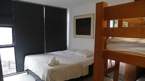 Un dormitorio con una cama, una cama nido de madera, una ventana y una puerta.