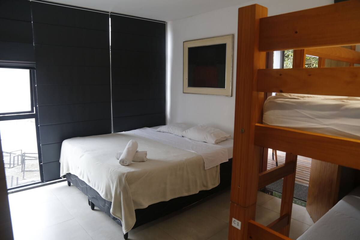 Un dormitorio con una cama, una cama nido de madera, una ventana y una puerta.