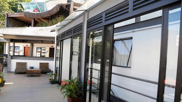 Un edificio moderno con ventanas amplias, un balcón y mesas al aire libre.
