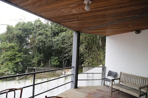 Un balcón con techo de madera, una banca y una silla.