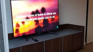 Un televisor de pantalla plana sobre un mueble de televisión de madera en una habitación con suelo de madera.