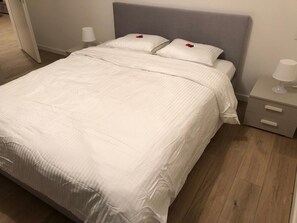 A cozy retreat awaits with a plush bed and a convenient bedside table.