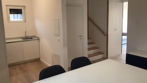 Una cocina moderna con un lavamanos integrado y un comedor con mesa y sillas blancas.