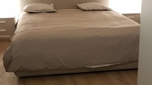 Un dormitorio con una cama grande, cabecera y piso de madera.