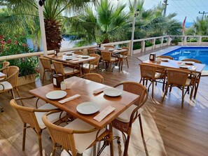 An outdoor dining area with wicker furniture and a pool.