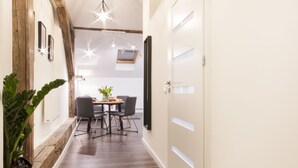 A hallway with wooden flooring, a dining area with a table and chairs, and a ceiling light fixture. - Aparthotel Floriańska 24 (Kraków)