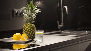A kitchen counter with a pineapple, lemons, and a glass of water. - Aparthotel Floriańska 24 (Kraków)