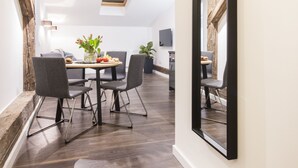 A modern dining area with a wooden table, chairs, and a ceiling light fixture. - Aparthotel Floriańska 24 (Kraków)