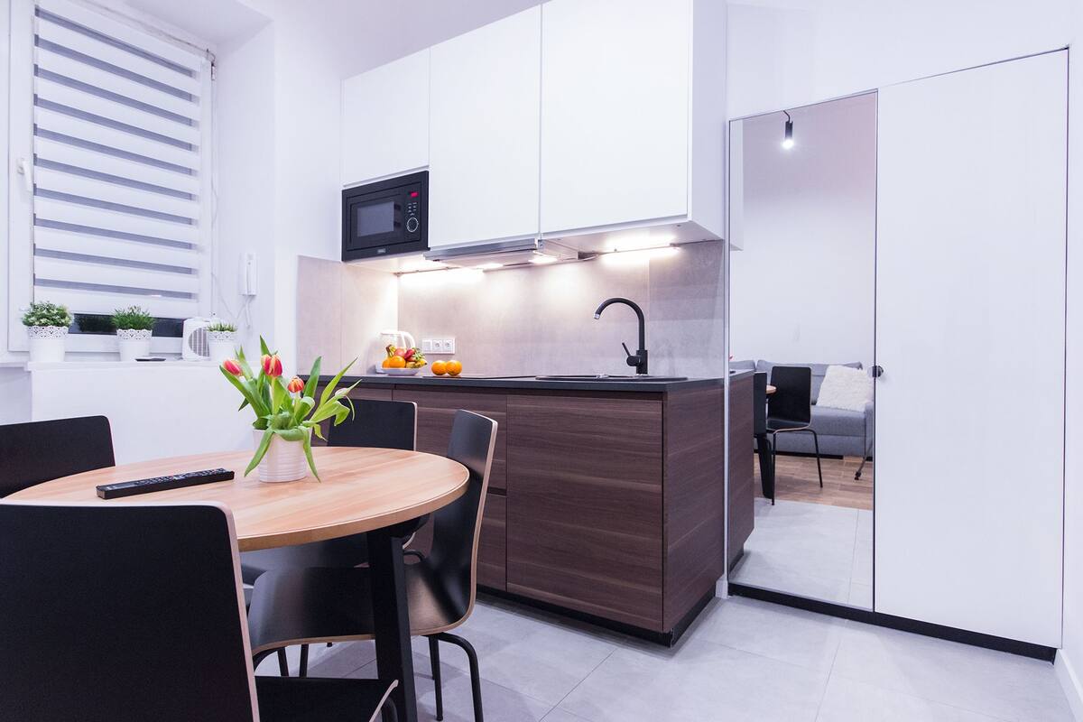 Una cocina compacta con microondas, lavamanos y comedor con mesa y sillas.