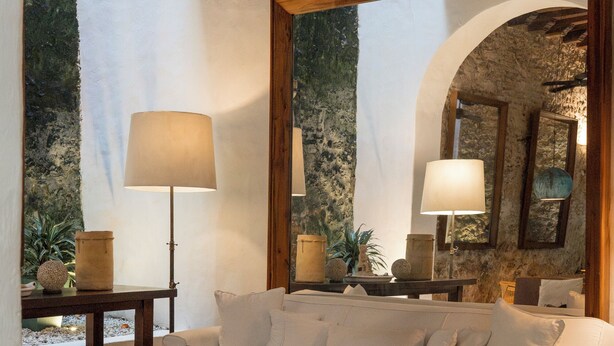 A cozy living room with a white sofa, a wicker bench, a coffee table with a bowl of nuts, and a large mirror reflecting the room. - Amarla Boutique Hotel Cartagena (Cartagena)
