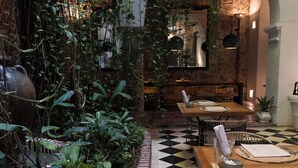 A restaurant with a checkered floor, wooden tables, and hanging plants. - Amarla Boutique Hotel Cartagena (Cartagena)