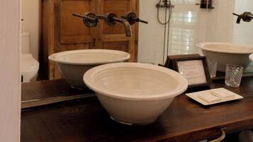 A bathroom with two large sinks, a wooden cabinet, a shower, and a towel rack.