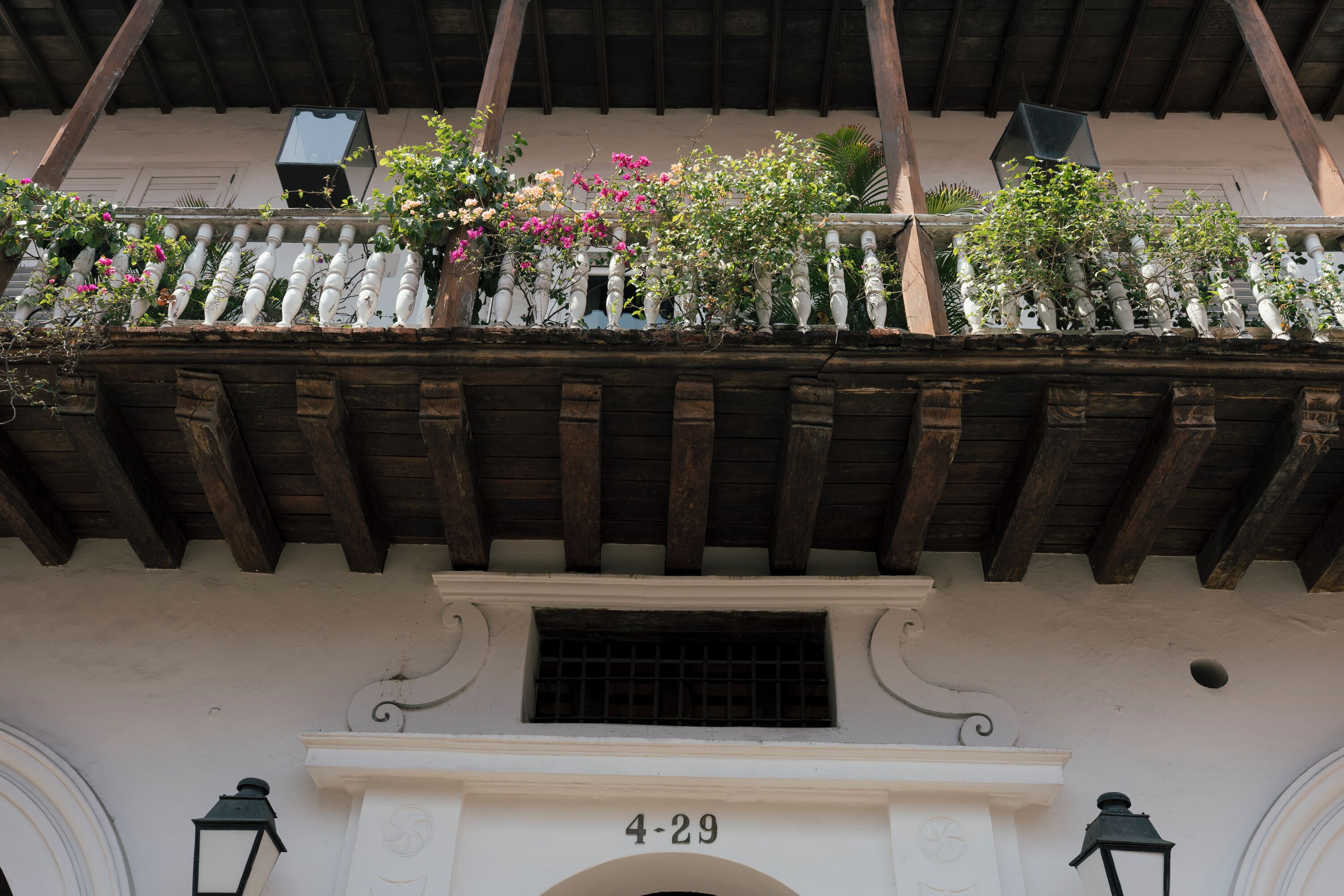 Eine Gebäudefassade mit Balkon, geschmückt mit Blumen, und der Hausnummer '4-29' über einem Eingang.