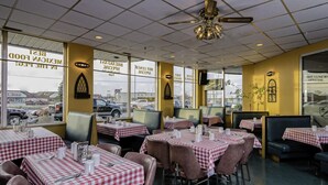 A restaurant with checkered tablecloths, booths, and a ceiling fan. - The New Cavalier Inn (Winnipeg)