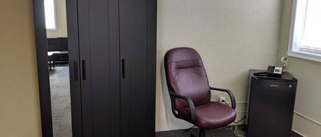 Una habitación con un armario grande, una silla de escritorio de cuero y un pequeño mueble negro.