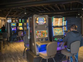 Un casino con múltiples máquinas tragamonedas y mesas de juego.