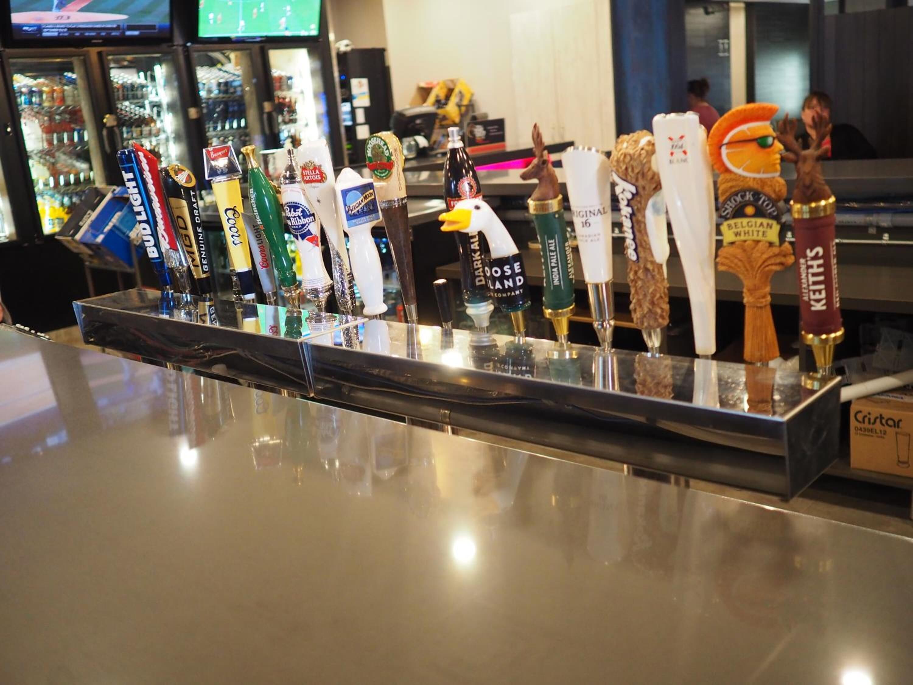 Zona de bar con diversas grifos de cerveza y una figura de mascota.
