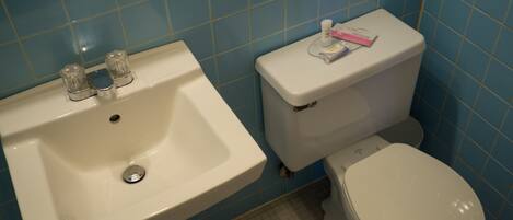 Et badeværelse med en hvid vask og toilet, blå flisevægge og et gulv med et gittermønster.