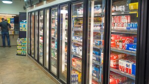 A refrigerated display case in a store with various beverages and snacks. - The New Cavalier Inn (Winnipeg)