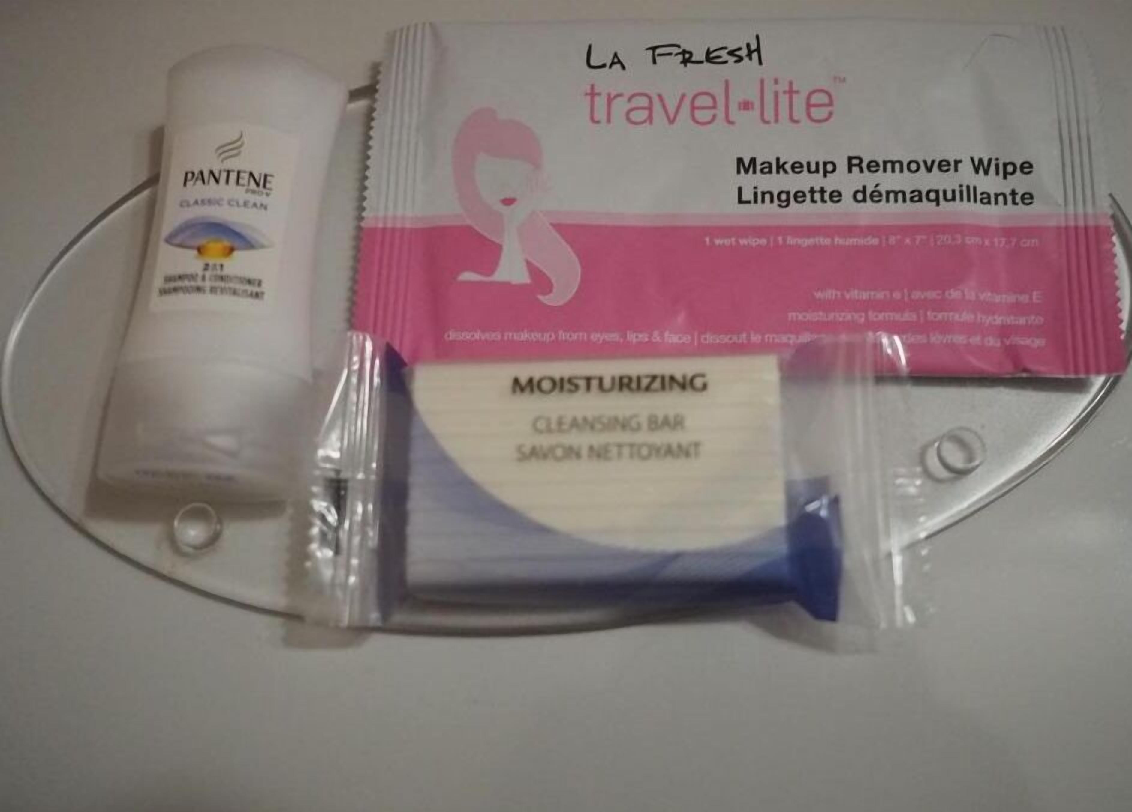 A travel kit with a Pantene shampoo, a La Fresh travel-lite makeup remover wipe, and a moisturizing cleansing bar.
