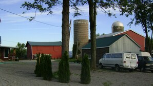 Un estacionamiento de grava con dos camionetas blancas, un granero rojo y un silo.