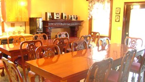 A dining room with a large wooden table and matching chairs, a fireplace, and kitchen cabinets in the background. - Room #7 We are only 30 min. away from  "BASEBALL HALL OF FAME" in Coopers Town . (Fort Plain)