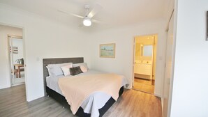 Um quarto com uma cama, um ventilador de teto e uma porta que dá para um banheiro.