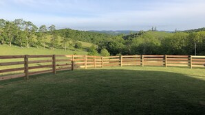 Un césped vallado con vistas a ondulantes colinas y árboles.
