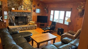 Un salón acogedor con chimenea de piedra, sofás de cuero, una mesa de centro de madera y un televisor.