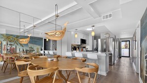 Une cuisine moderne équipée d’appareils électroménagers en acier inoxydable, un coin repas avec des meubles en bois et une fresque murale.